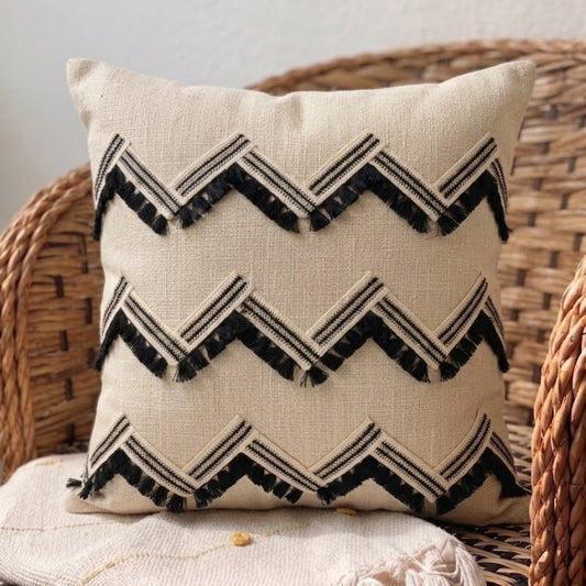 Decorative pillow with black zigzag pattern on a wicker chair