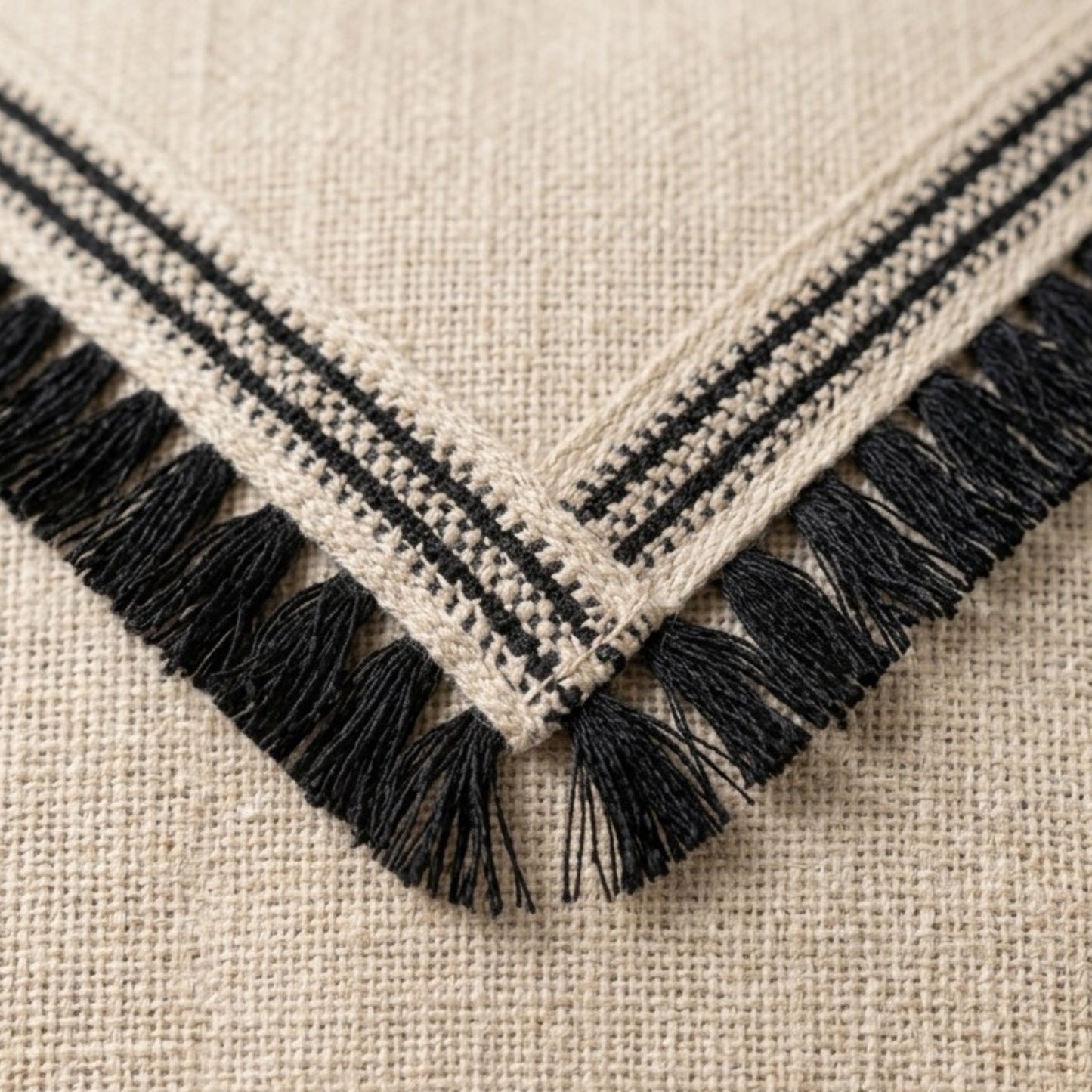Close-up of a textured fabric with black stripes and fringes on a beige background