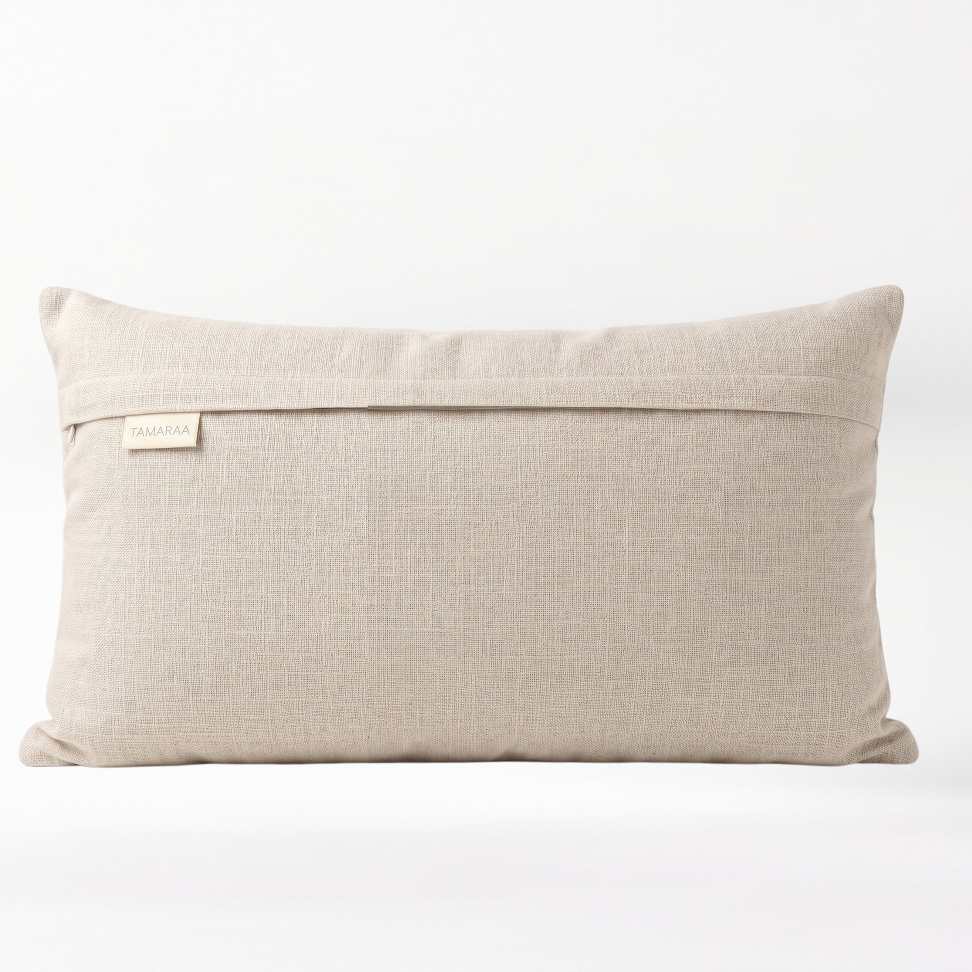 Beige pillow with a brand label on a white background