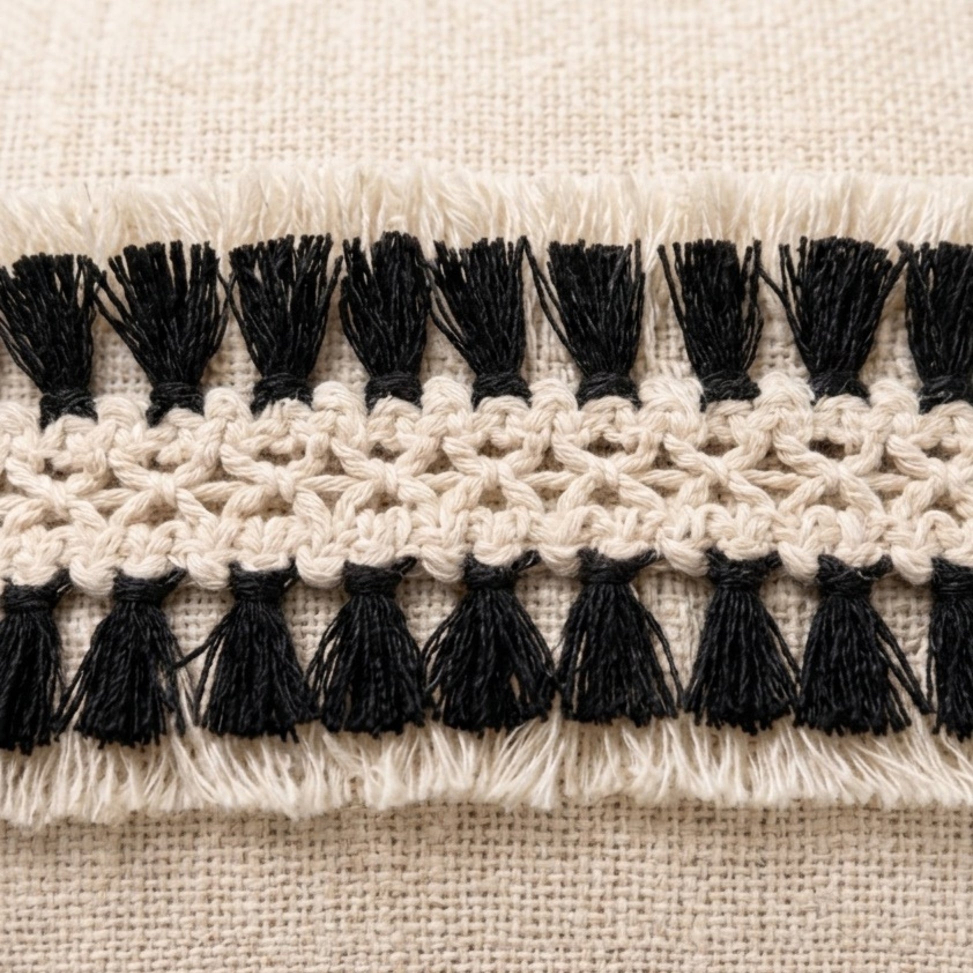 Close-up of black tassels on a beige fabric background