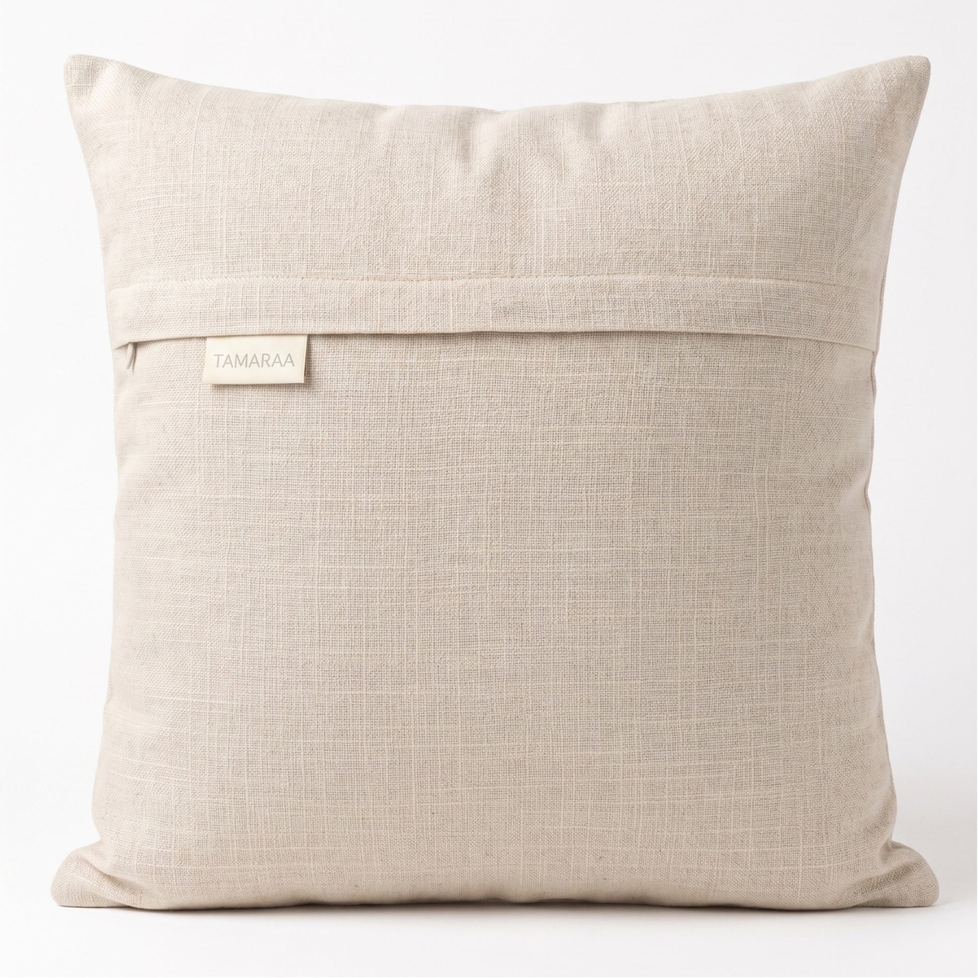 Beige pillow with a visible brand label on a white background