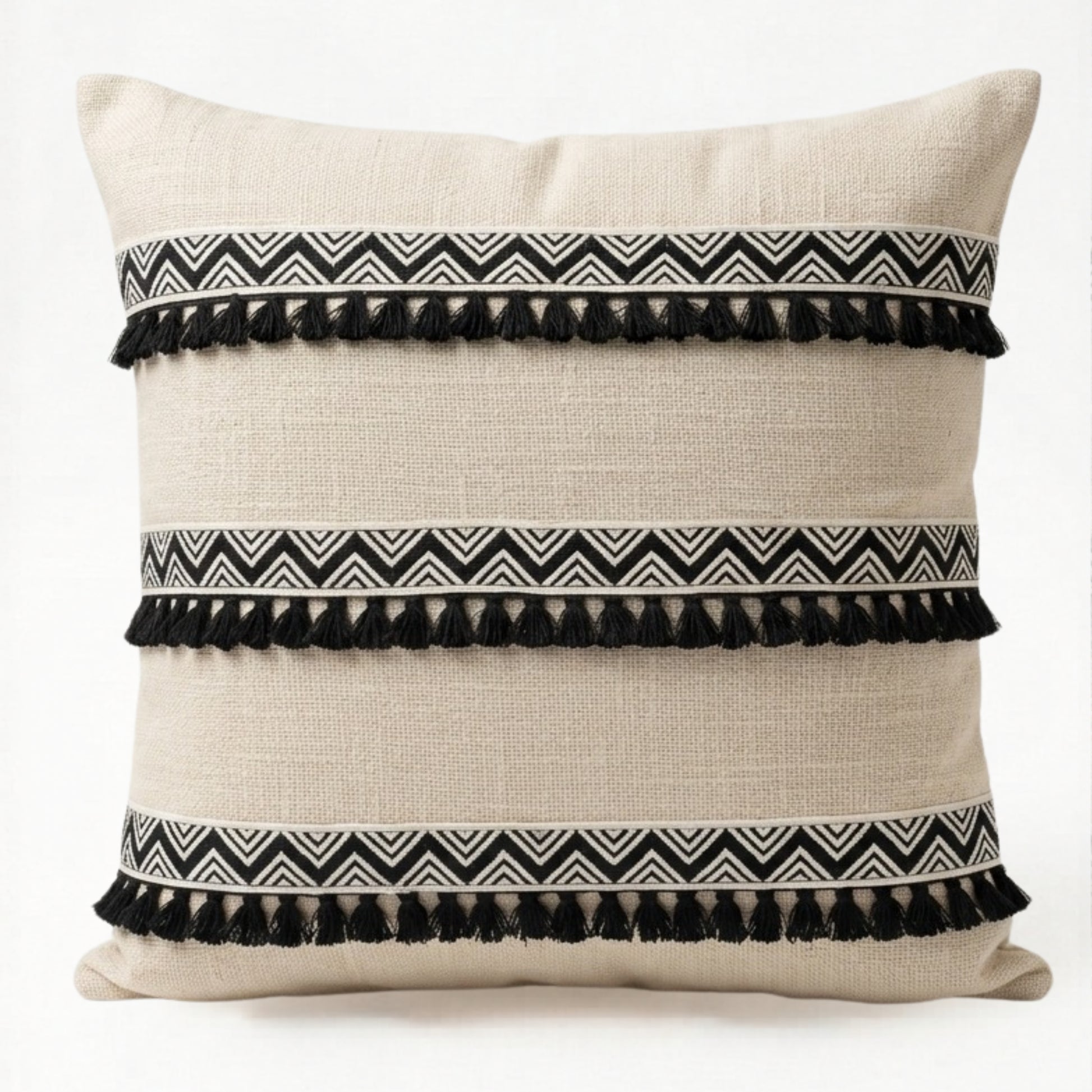 Decorative pillow with black and white zigzag patterns and tassels on a beige background